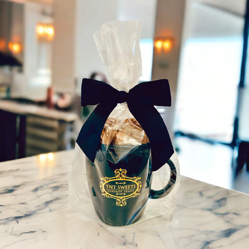 Candy filled in an 18oz mug wrapped in cellophane with a black bow on a marble countertop.
