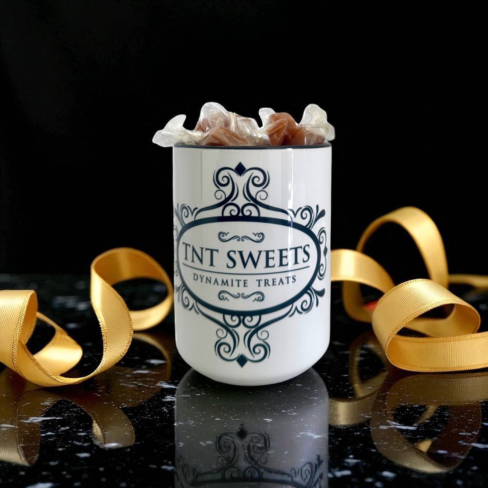 Luxe white 11oz gift mug with caramels on a black marble countertop with a gold ribbon scattered.