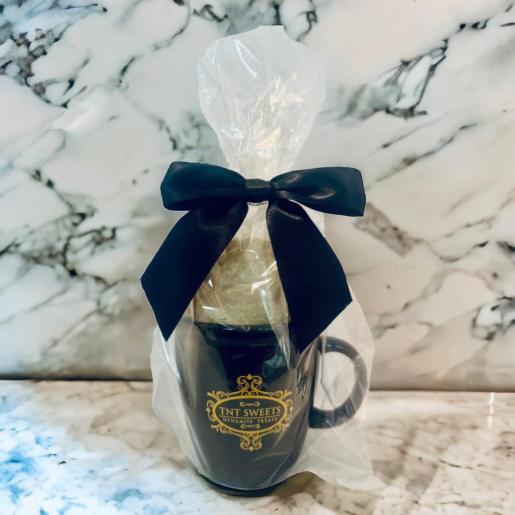 Lemon Glazed cookies filled in an 18oz mug wrapped in cellophane with a black bow on a marble countertop.