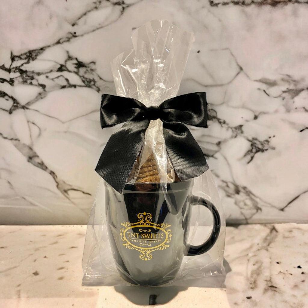 Peanut Butter cookies filled in an 18oz mug wrapped in cellophane with a black bow on a marble countertop.