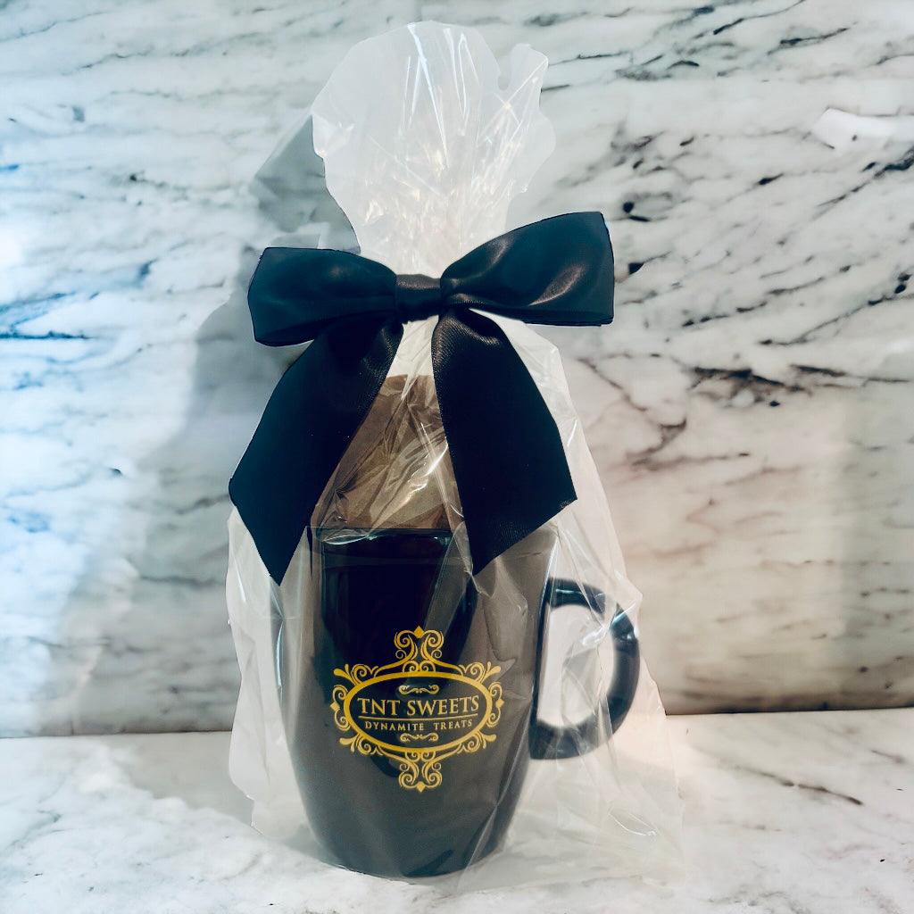 Snickerdoodle cookies filled in an 18oz mug wrapped in cellophane with a black bow on a marble countertop.
