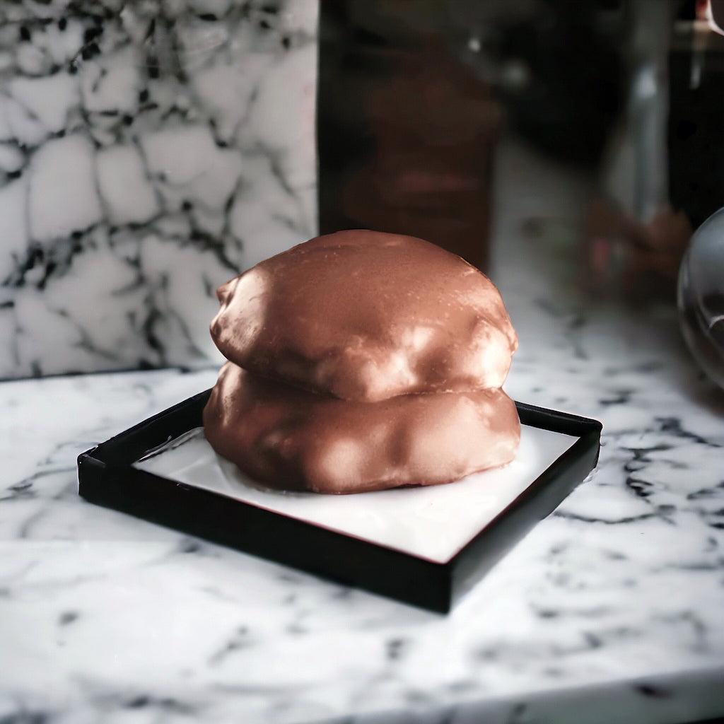 Two dark chocolate turtles on a tray on a marble countertop.