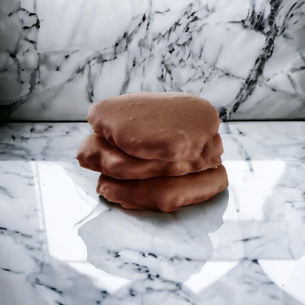 Stack of three Milk Chocolate chews on a marble countertop.