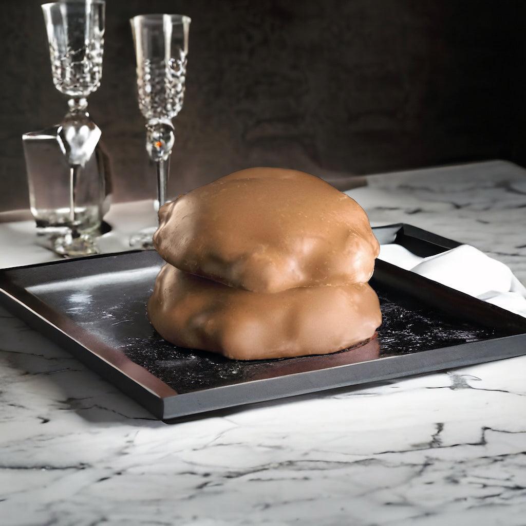 Two milk chocolate turtles on a tray on a marble countertop.