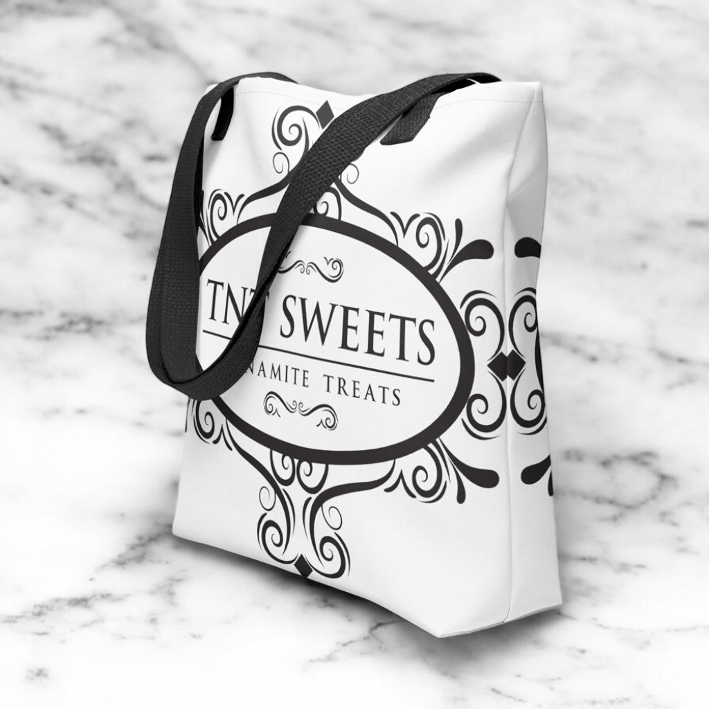 White tote bag with a black TNT Sweets logo on a marble background.