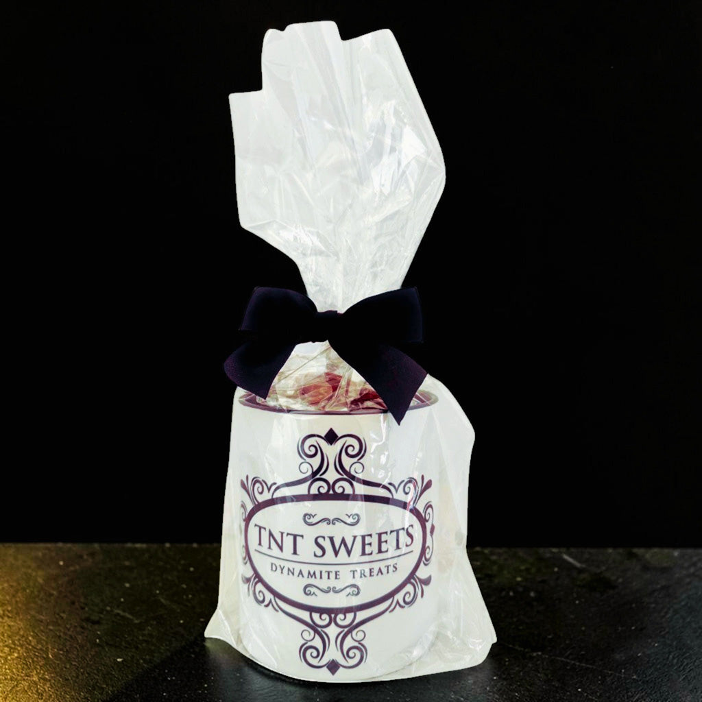 TNT Sweets 11-ounce Alabaster Edition mug gift wrapped in clear cellophane with a black satin bow.
