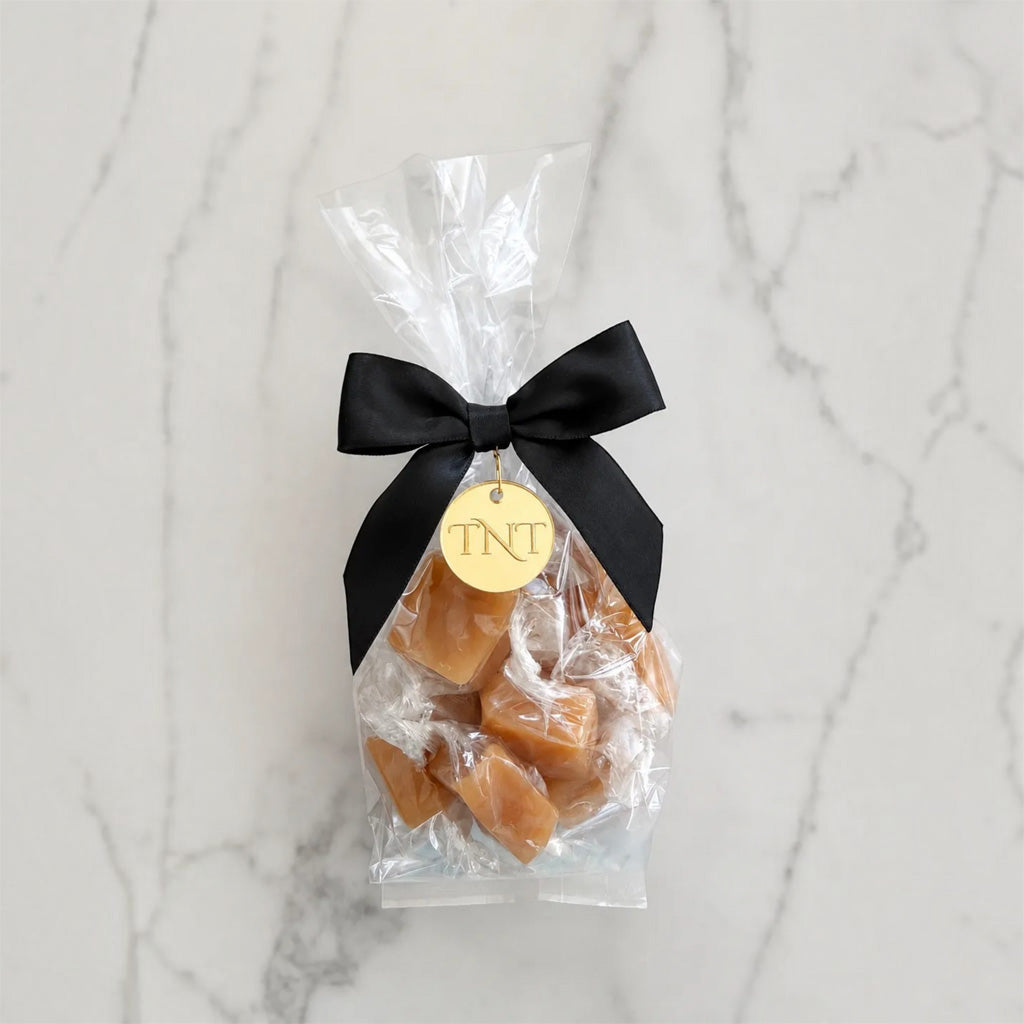 The Accent caramel favor by TNT Sweets with individually wrapped Amber Velvet sea salt caramels, black satin ribbon, and gold TNT medallion.