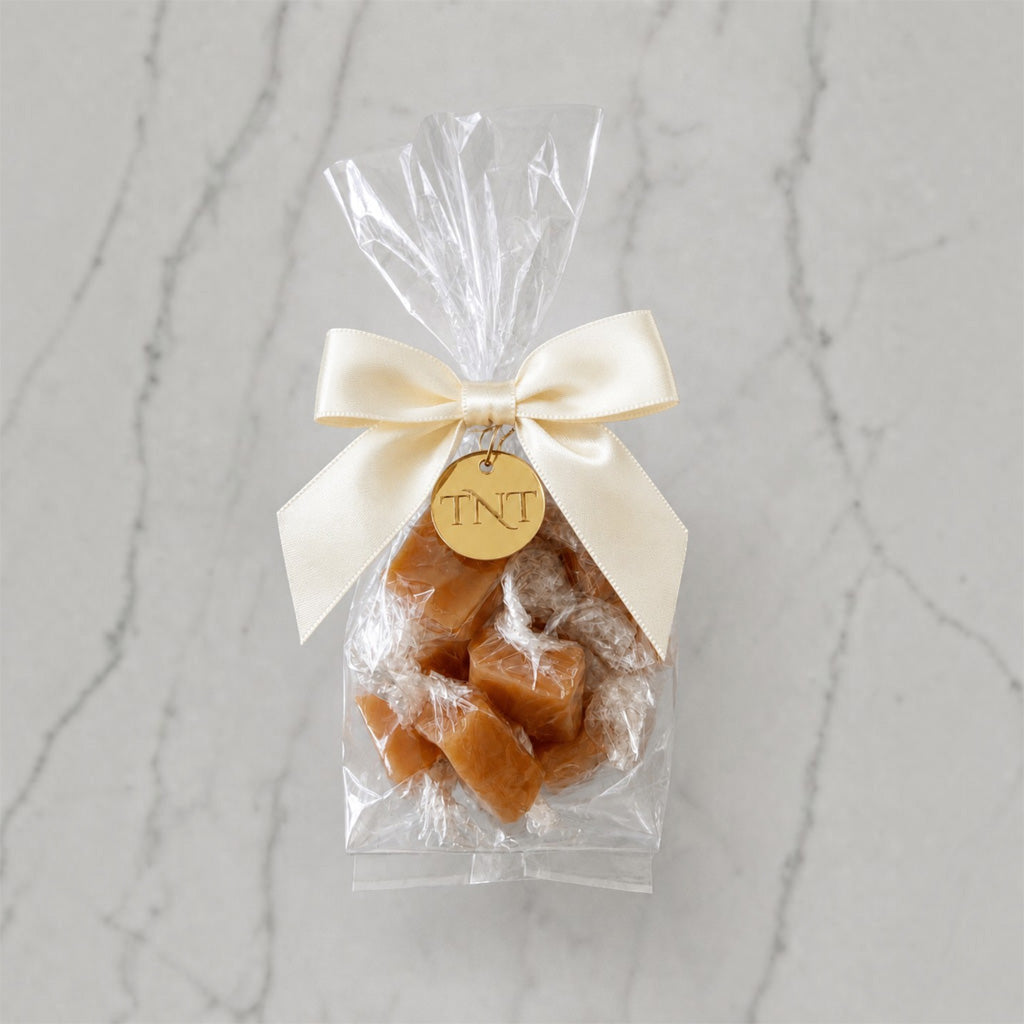 The Accent caramel favor by TNT Sweets with individually wrapped Amber Velvet sea salt caramels, ivory satin ribbon, and gold TNT medallion.
