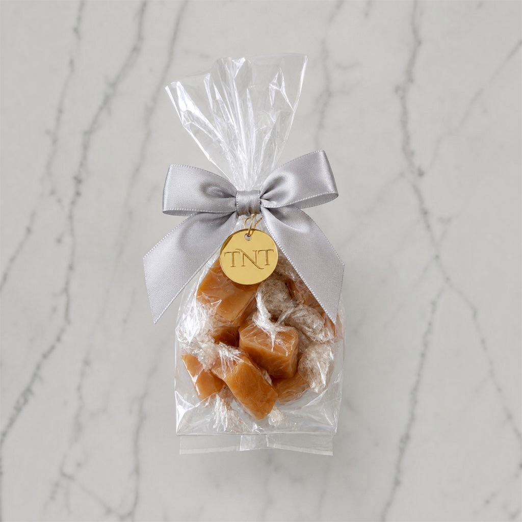 The Accent caramel favor by TNT Sweets with individually wrapped Amber Velvet sea salt caramels, silver satin ribbon, and gold TNT medallion.