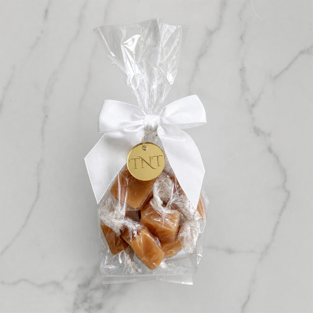 The Accent caramel favor by TNT Sweets with individually wrapped Amber Velvet sea salt caramels, white satin ribbon, and gold TNT medallion.
