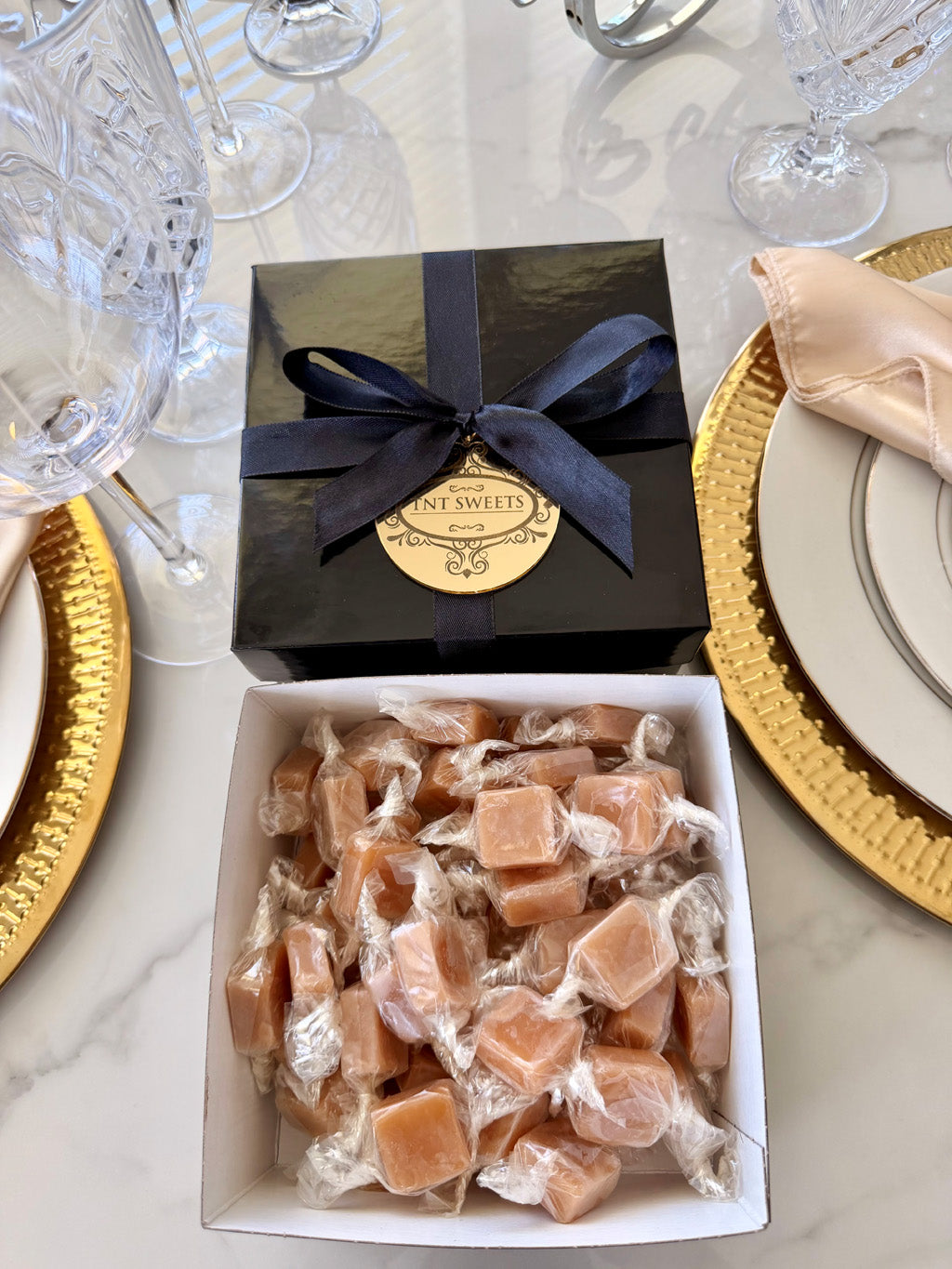 One pound of Amber Velvet sea salt caramels from TNT Sweets in the black Keepsake Box tied with a black satin ribbon and finished the gold acrylic medallion.