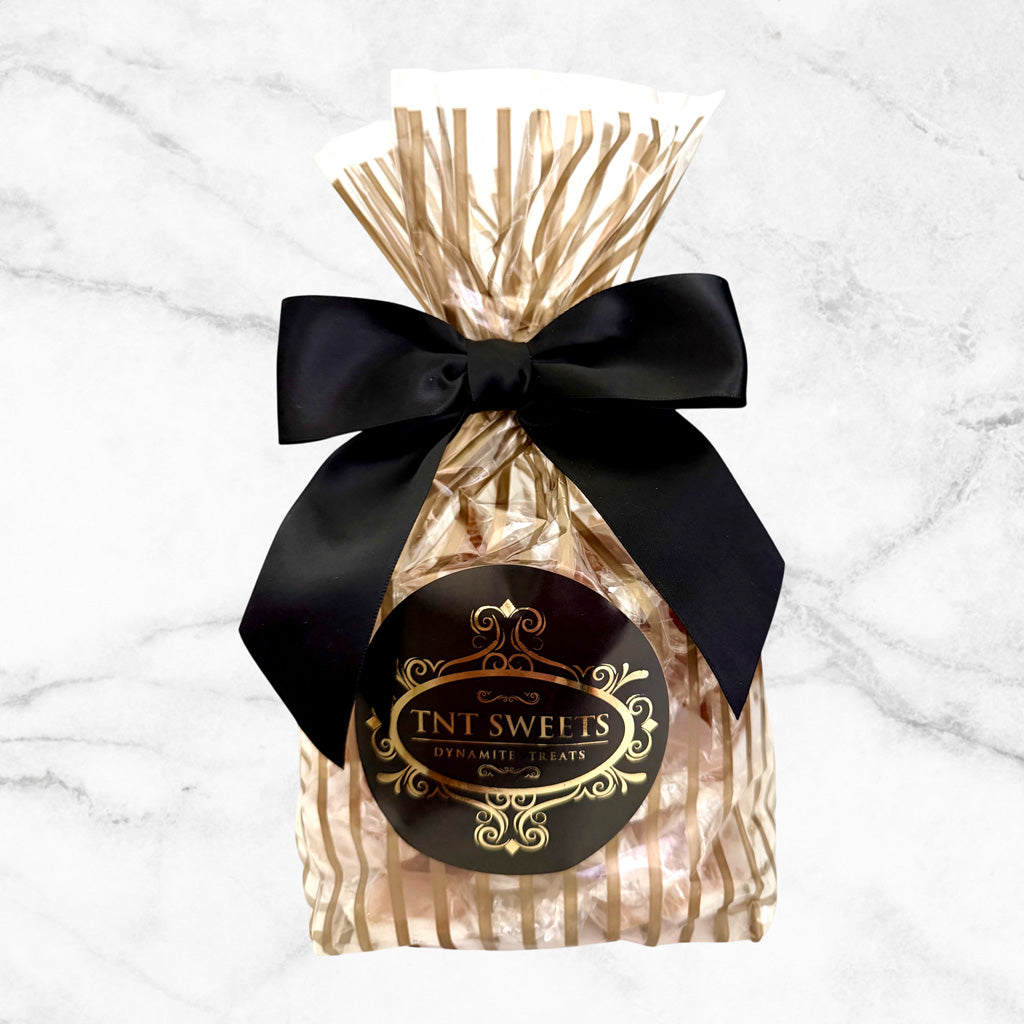 One pound of Amber Velvet caramels from TNT Sweets in ths Gold Stripe Wrap with a black satin bow finished with the TNT Sweets signature seal. 