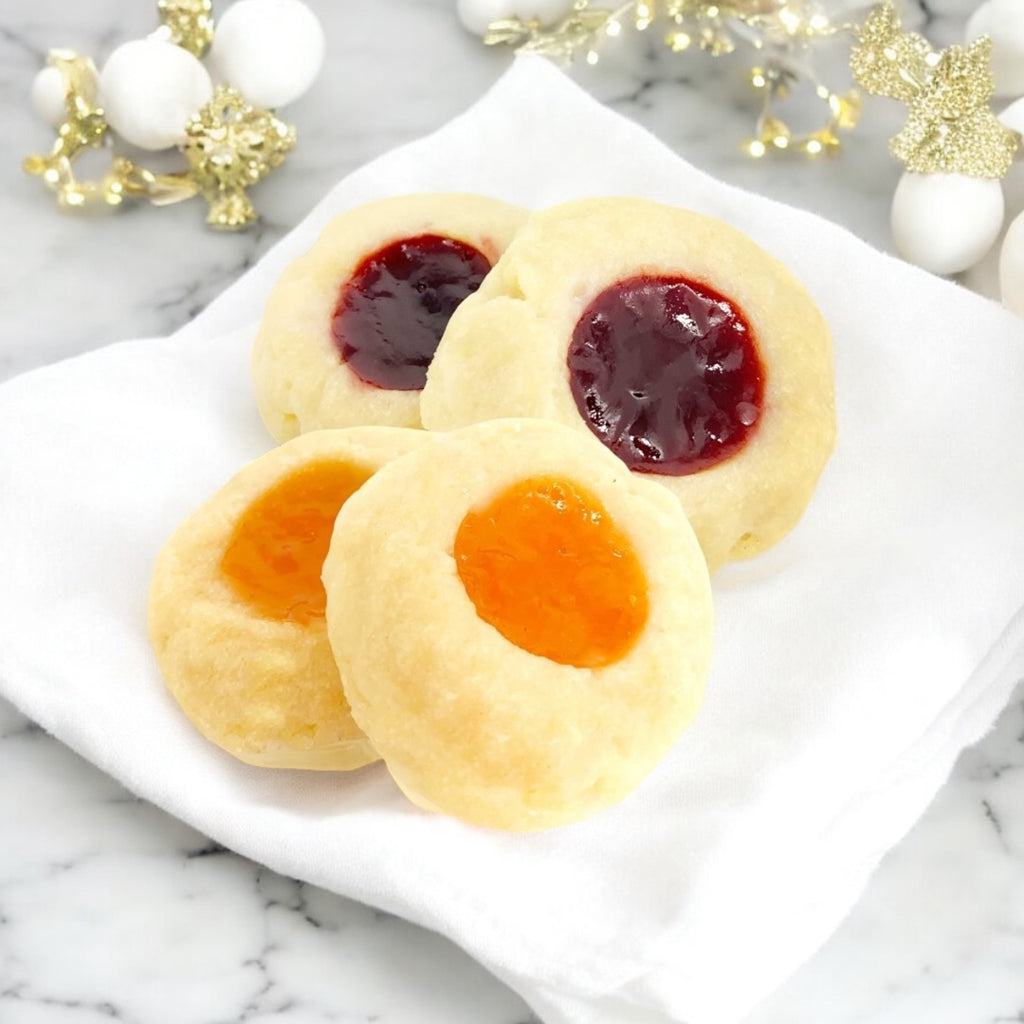 Raspberry and Apricot Thumbprints on a white linen napkin on a white marble countertop with white and gold decor in the background. 