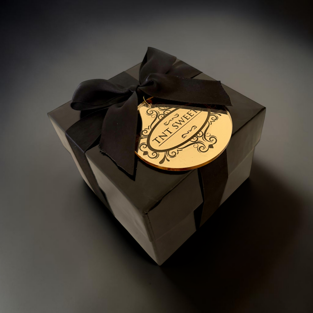 Gift box with a black ribbon and decorative label on a dark background