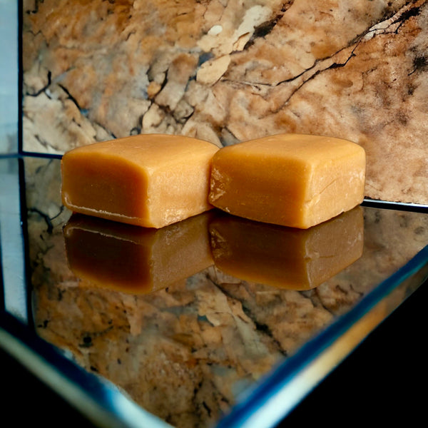 Two caramels on a mirrored marble countertop and a marble backdrop.