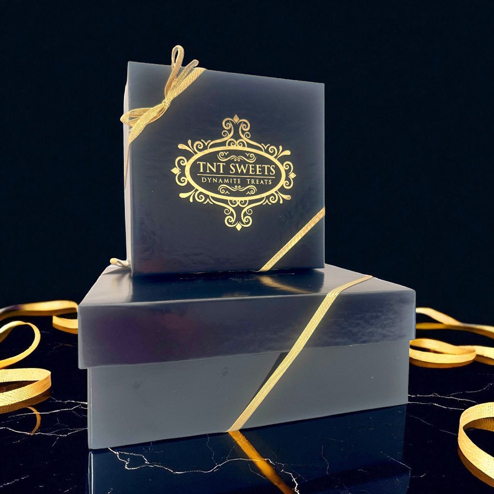Black gift box with gold ribbon and TNT Sweets logo on a dark background.