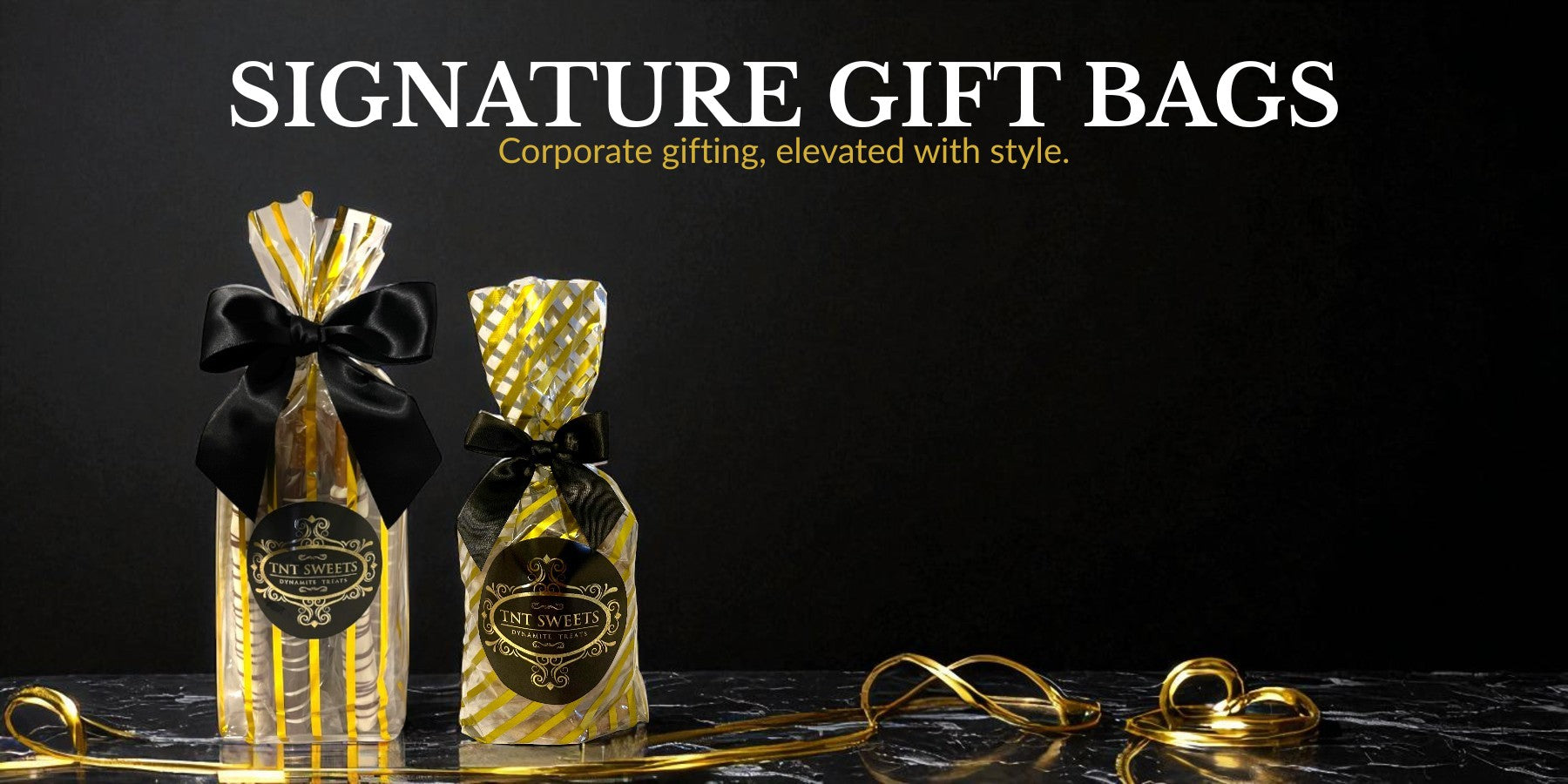 Gift bag of pretzels and a gift bag of cookies with a black marble background and gold ribbons.