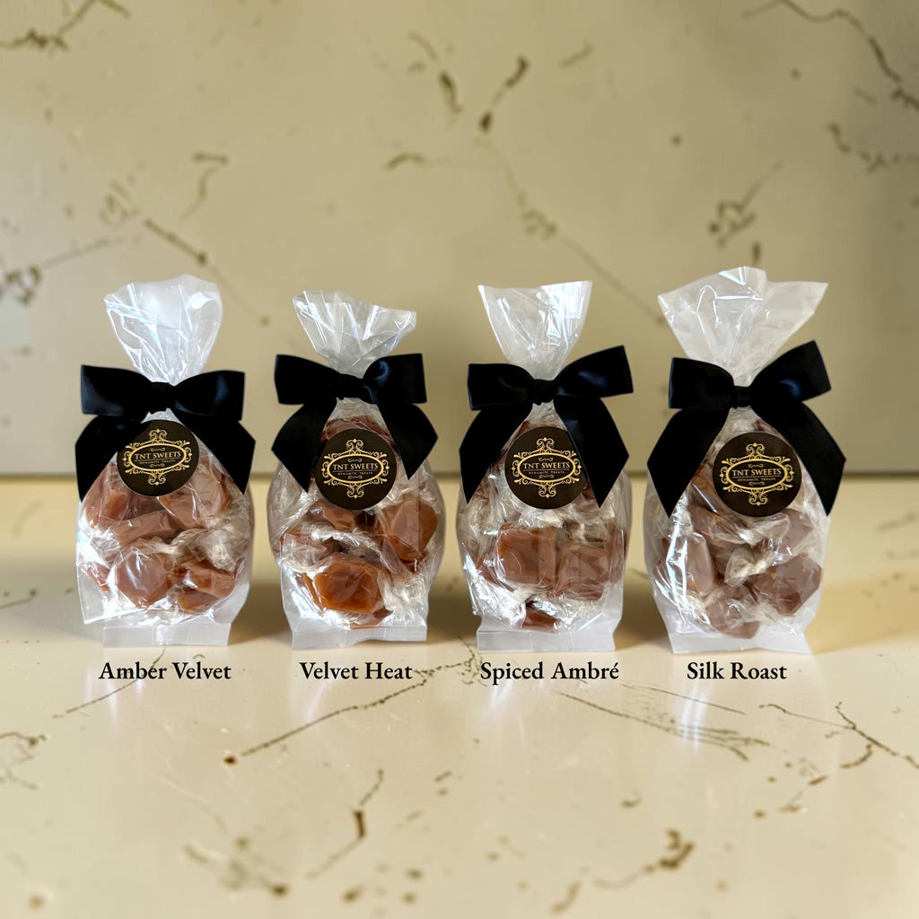 The Crescendo 15-piece caramel flight featuring Amber Velvet, Velvet Heat, Spiced Ambré, and Silk Roast on a cream marble background.