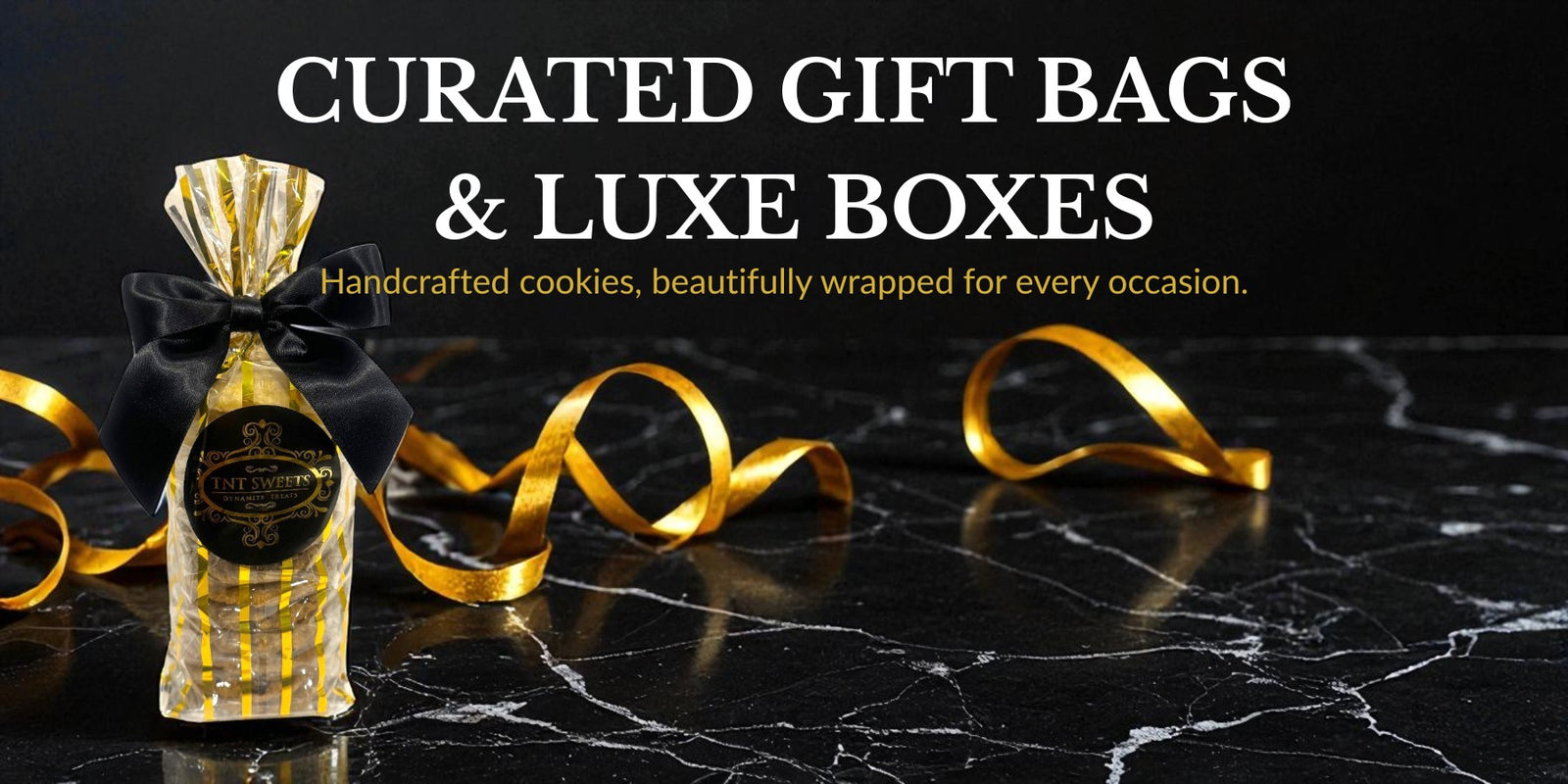 Gold gift bag with decorative ribbon on a black marble surface, promoting curated gift bags and luxe boxes.