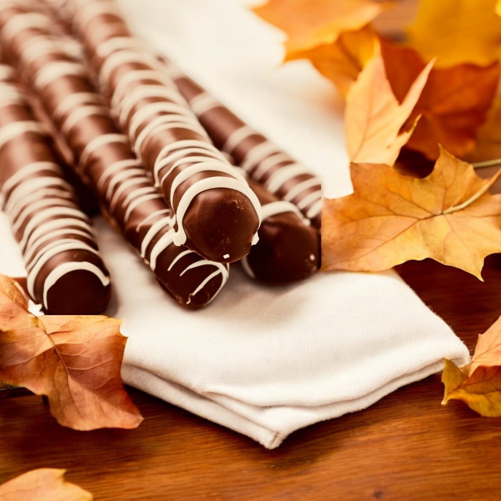 Stack of dark chocolate pretzels with a blurred background with scattered fall leaves.