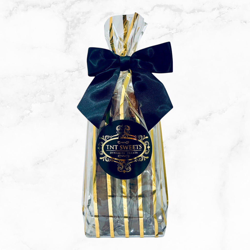 Gift bag with a black bow and TNT Sweets logo on a marble background.