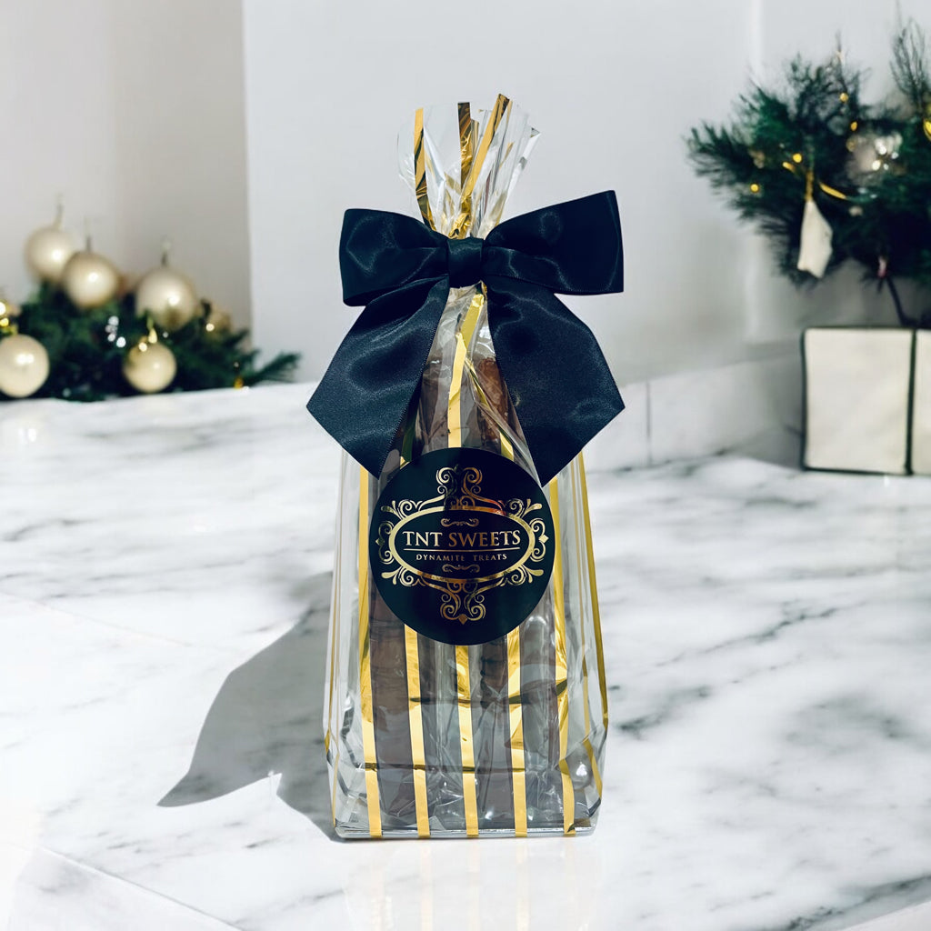 One dozen dark chocolate pretzels on a marble countertop with holiday decor in the background.