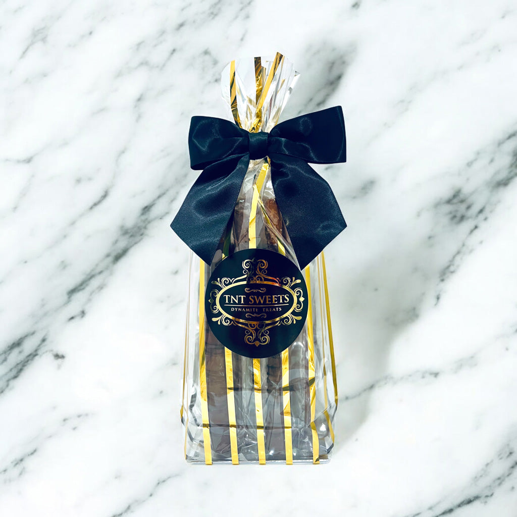 Gift bag with a black bow andTNT Sweets label on a marble background.