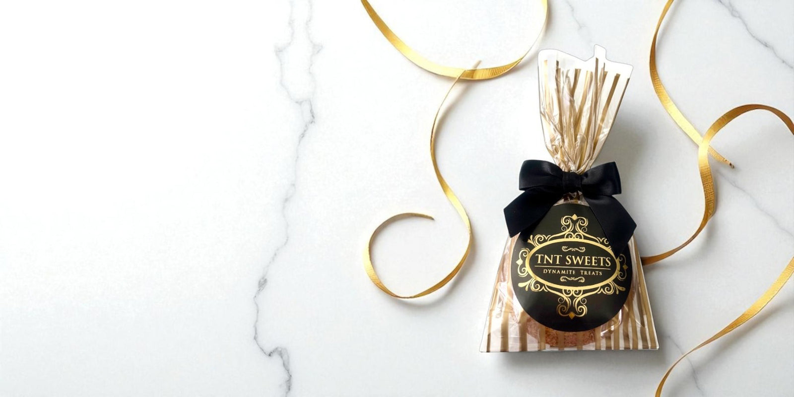 Banner of a cookie favor in a gold striped gift bag with decorative gold swirls. 