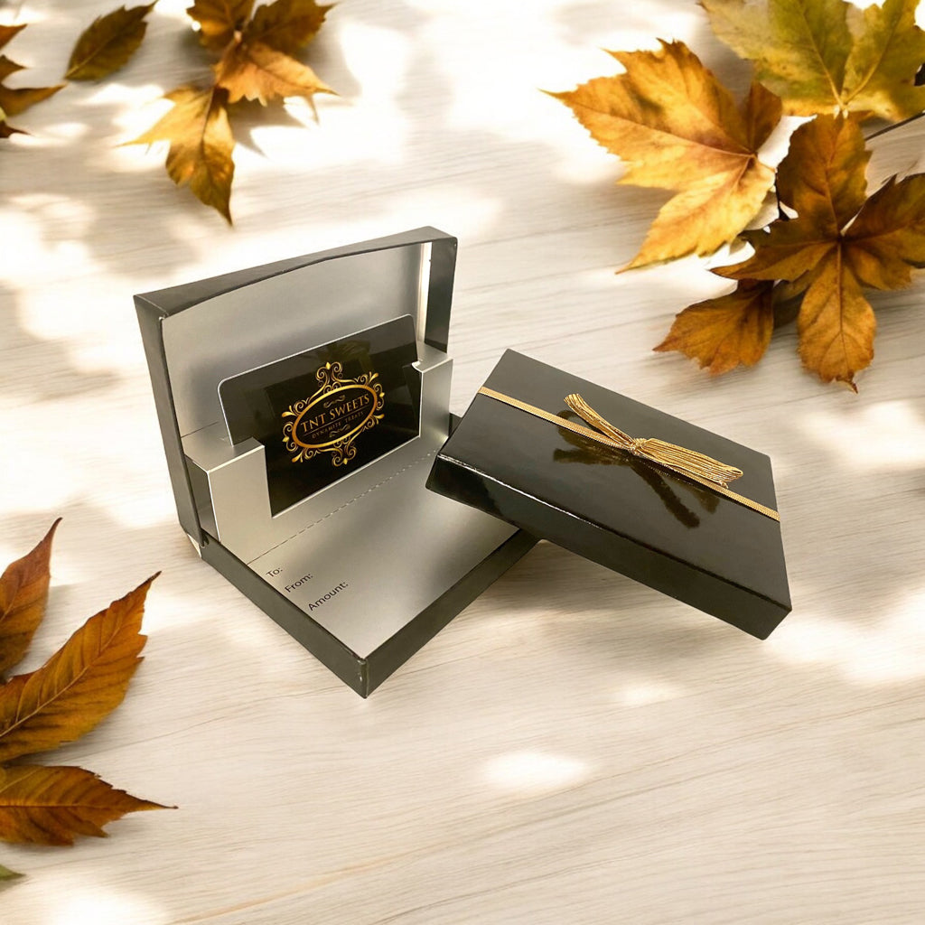 TNT Sweets gift card box on a wood countertop with scattered fall leaves.