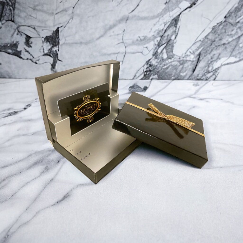 TNT Sweets Gift Card in an elegant black gift card box on a marble countertop.