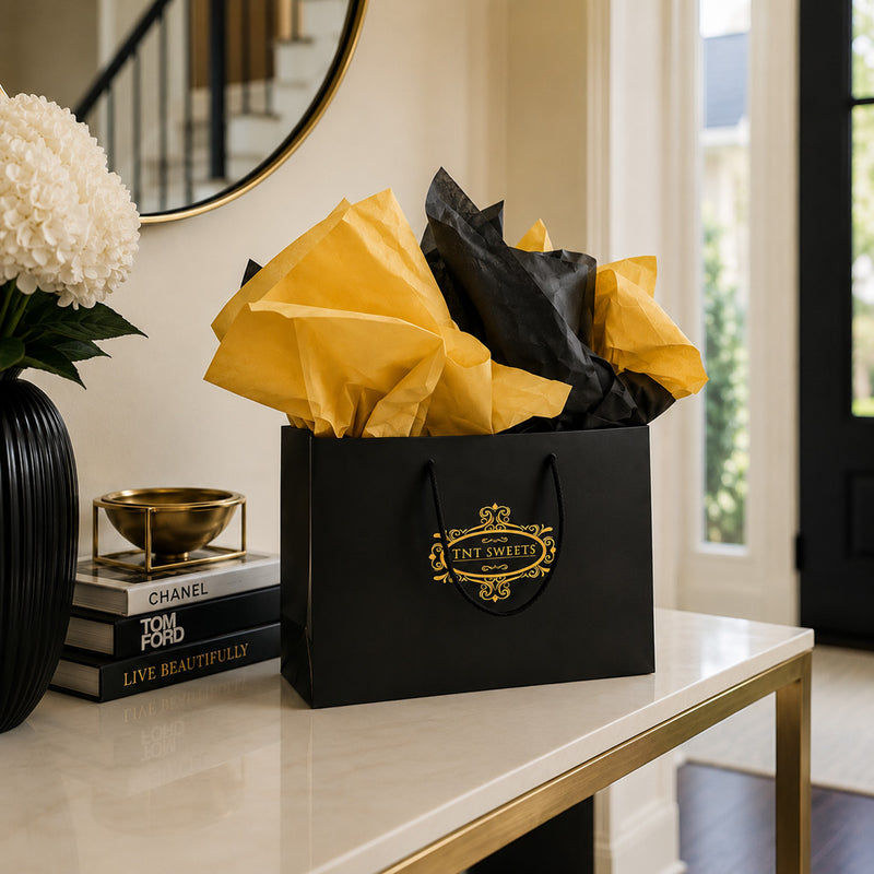 TNT Sweets black and gold gift bag with gold and black tissue paper displayed on an entryway console table for Devonshire local delivery.