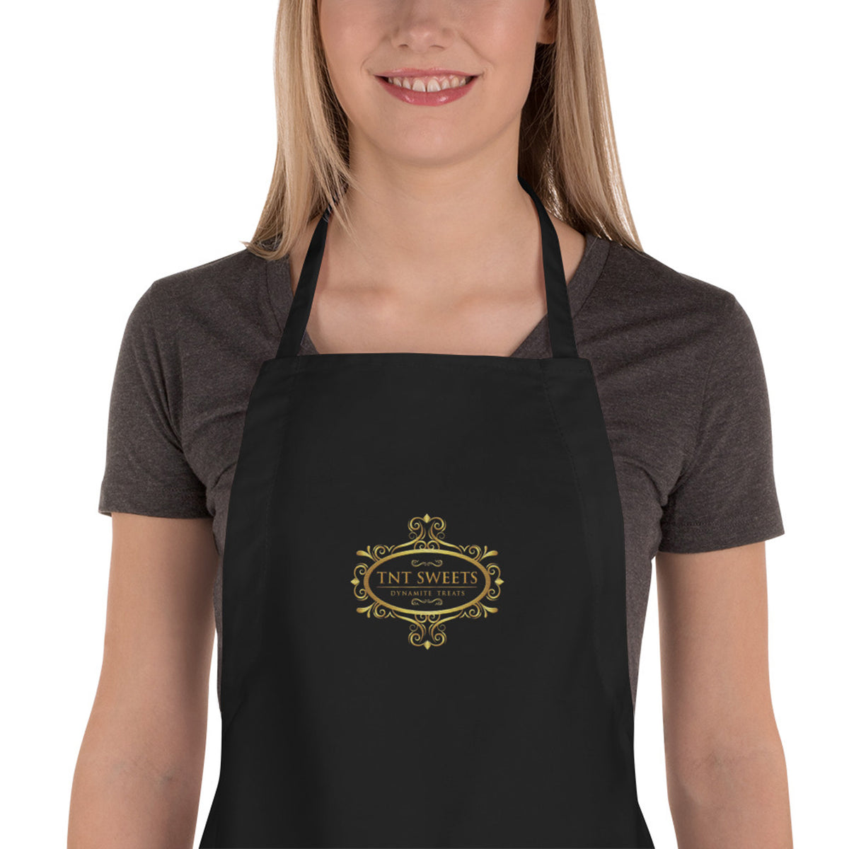 A person wearing a black apron with an embroidered logo on the front