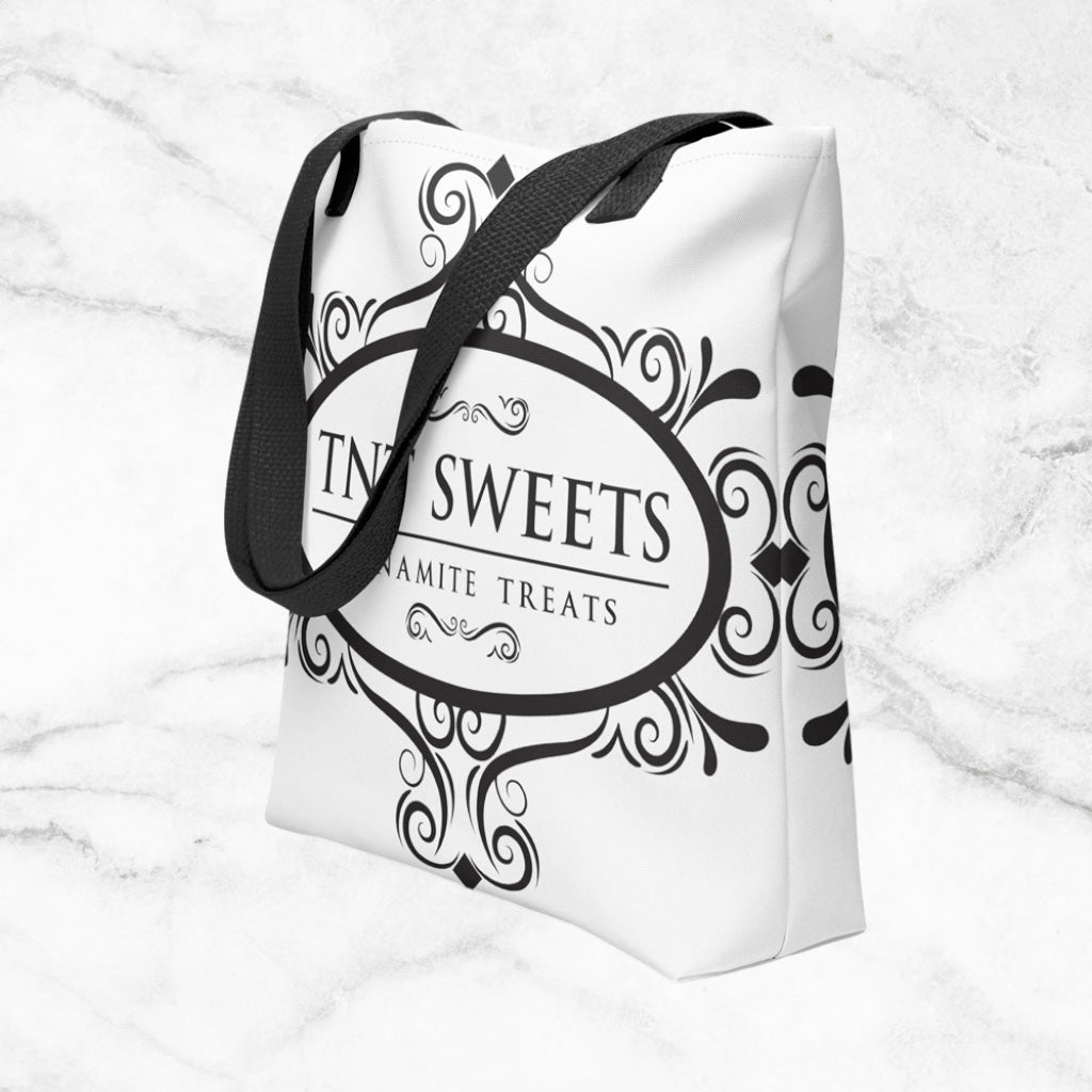 White tote bag with a black TNT Sweets logo on a marble background.