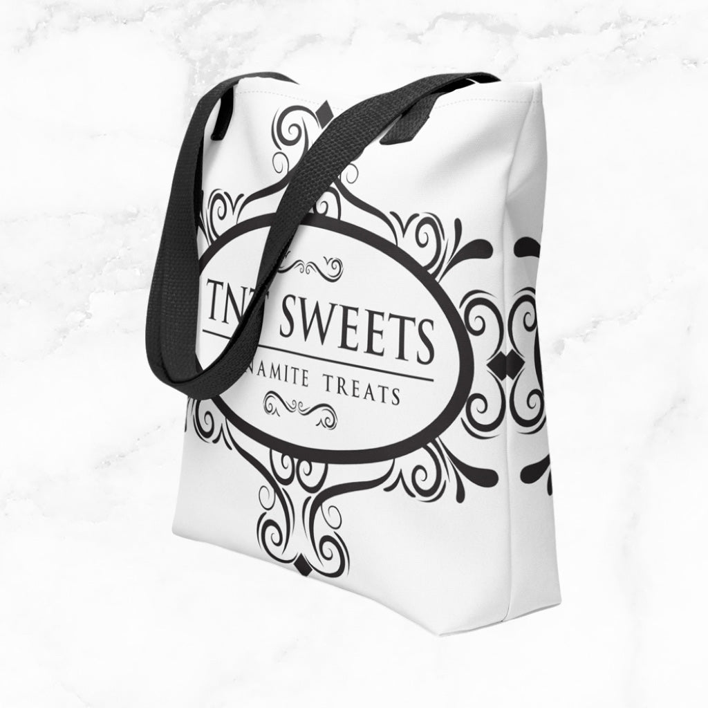 White tote bag with a black TNT Sweets logo on a marble background.