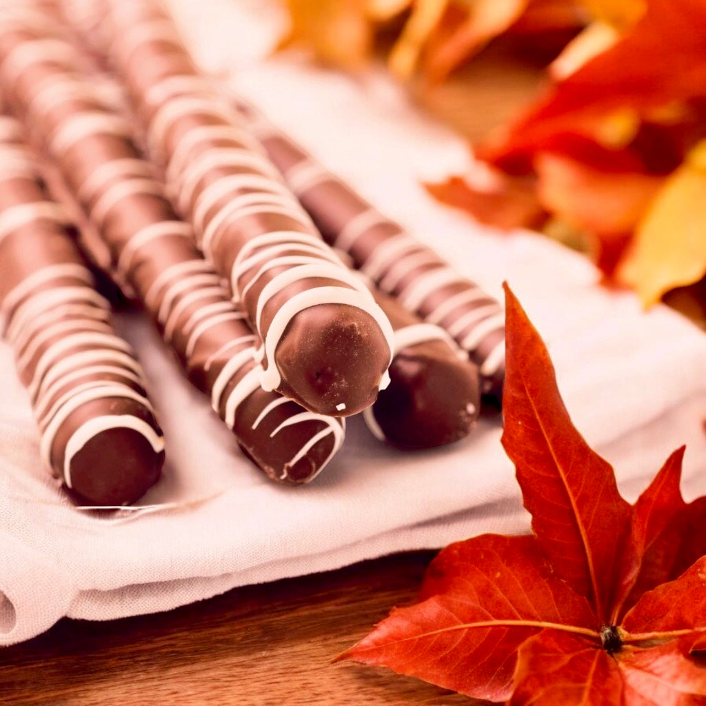 Stack of milk chocolate pretzels with a blurred background and scattered fall leaves.