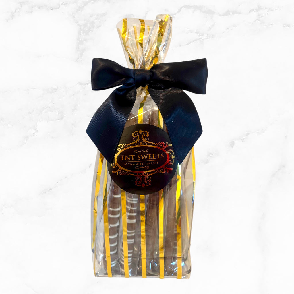 Milk chocolate pretzels in a gold striped gift bag on a marble countertop.