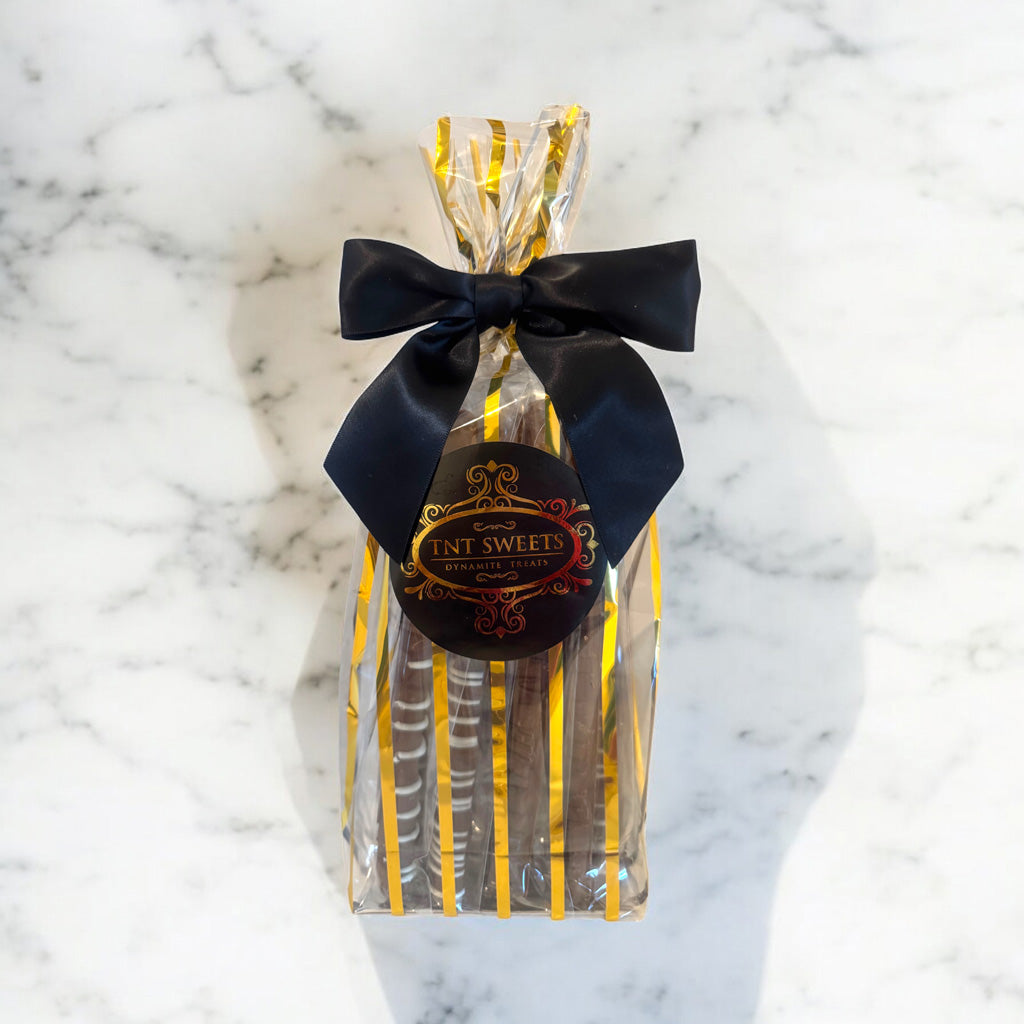 Milk chocolate pretzels in a gold striped gift bag on a marble countertop.