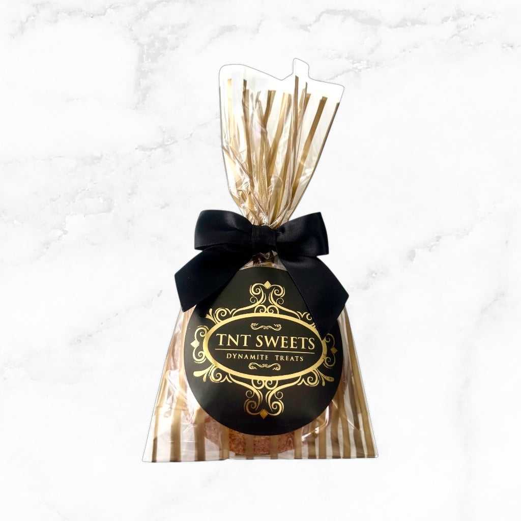 One cookie in a gold striped bag with black bow on a marble background.