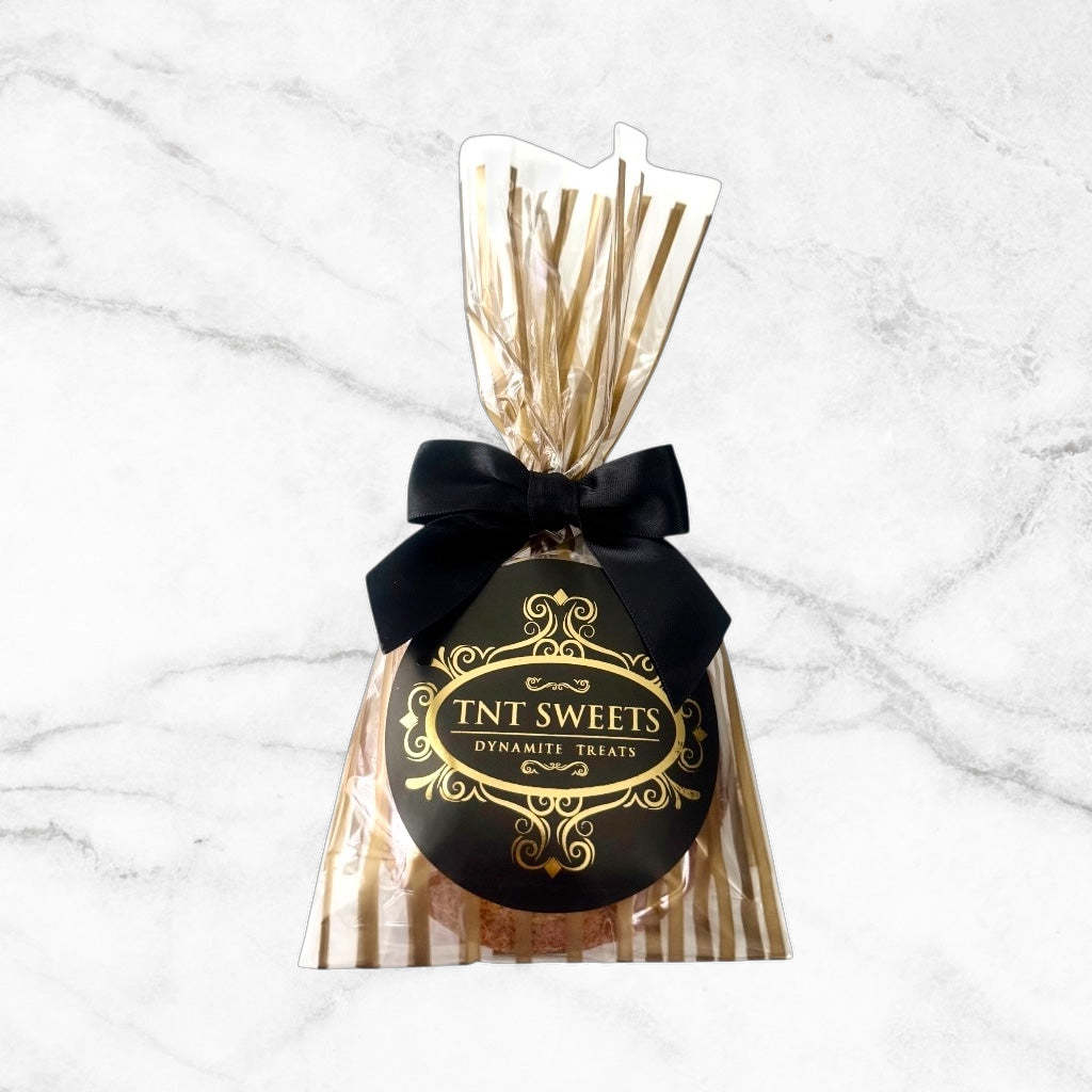 One cookie in a gold striped gift bag with black bow and logo.