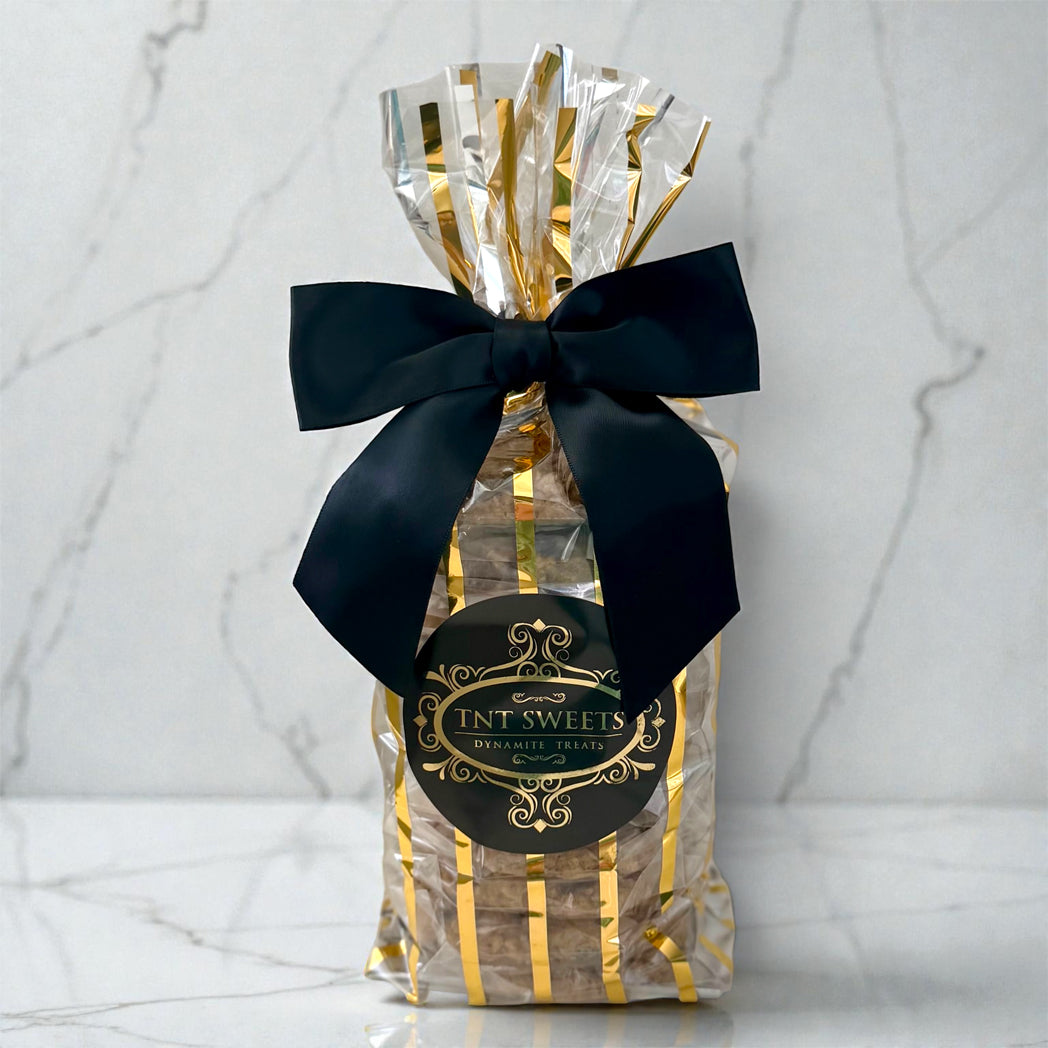 Gift bag with black bow and 'FNT SWEETS' label on a marble background