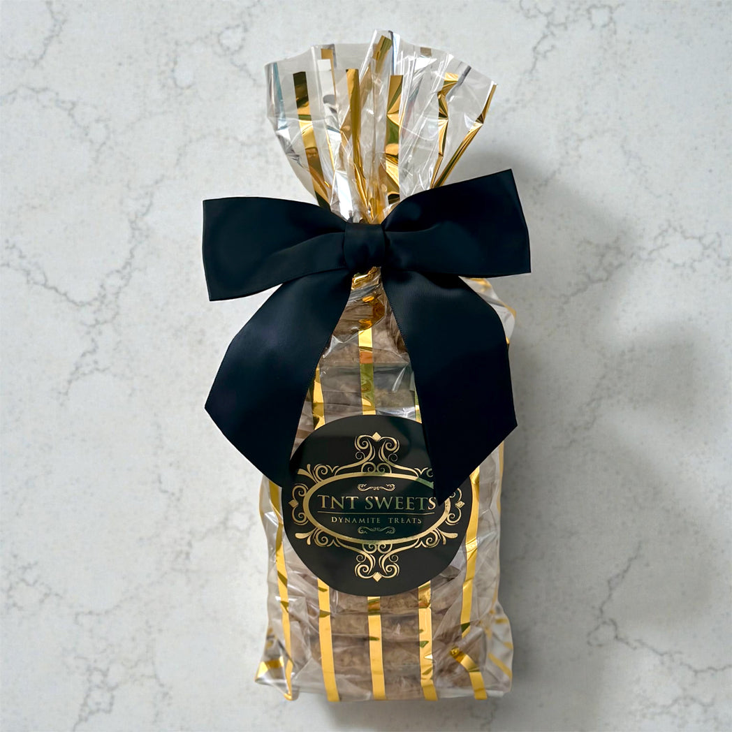 Gift bag with black bow and 'FNT SWEETS' label on a marble background
