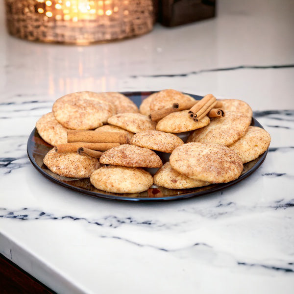 Plate of snickerdoodles on a white marble countertop with a gold light accent in the background.