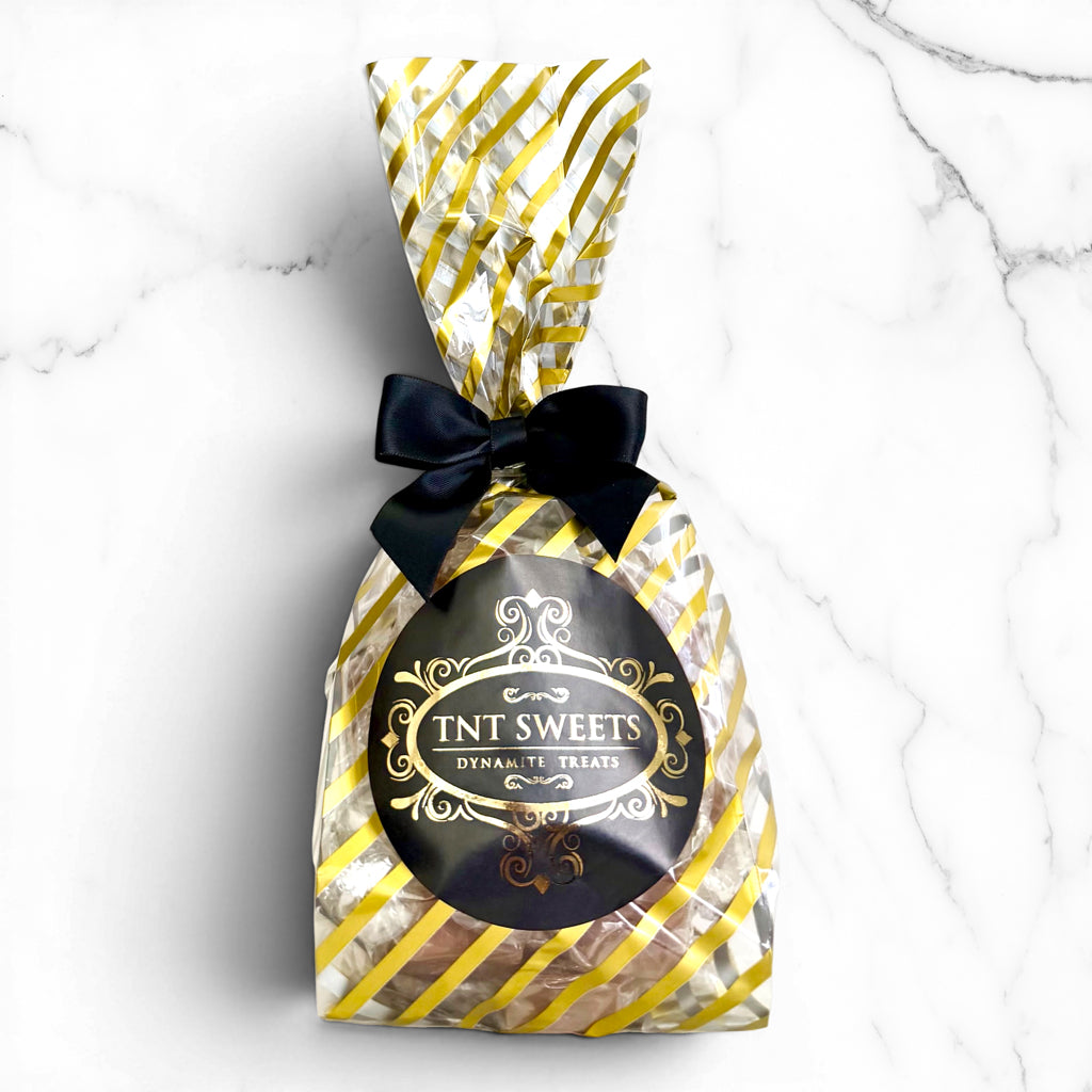 Gold striped bag filled with caramels with a black logo label and black bow.