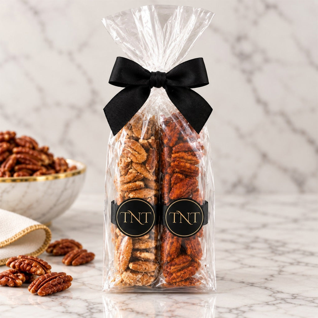 The Ensemble four-flavor pecan flight with four 2-ounce pecan sleeves in a clear gusset bag with black grosgrain ribbon and TNT monogram.