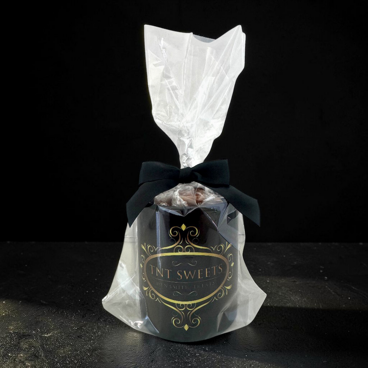 TNT Sweets 11-ounce Obsidian Edition mug gift wrapped in clear cellophane with a black satin bow.