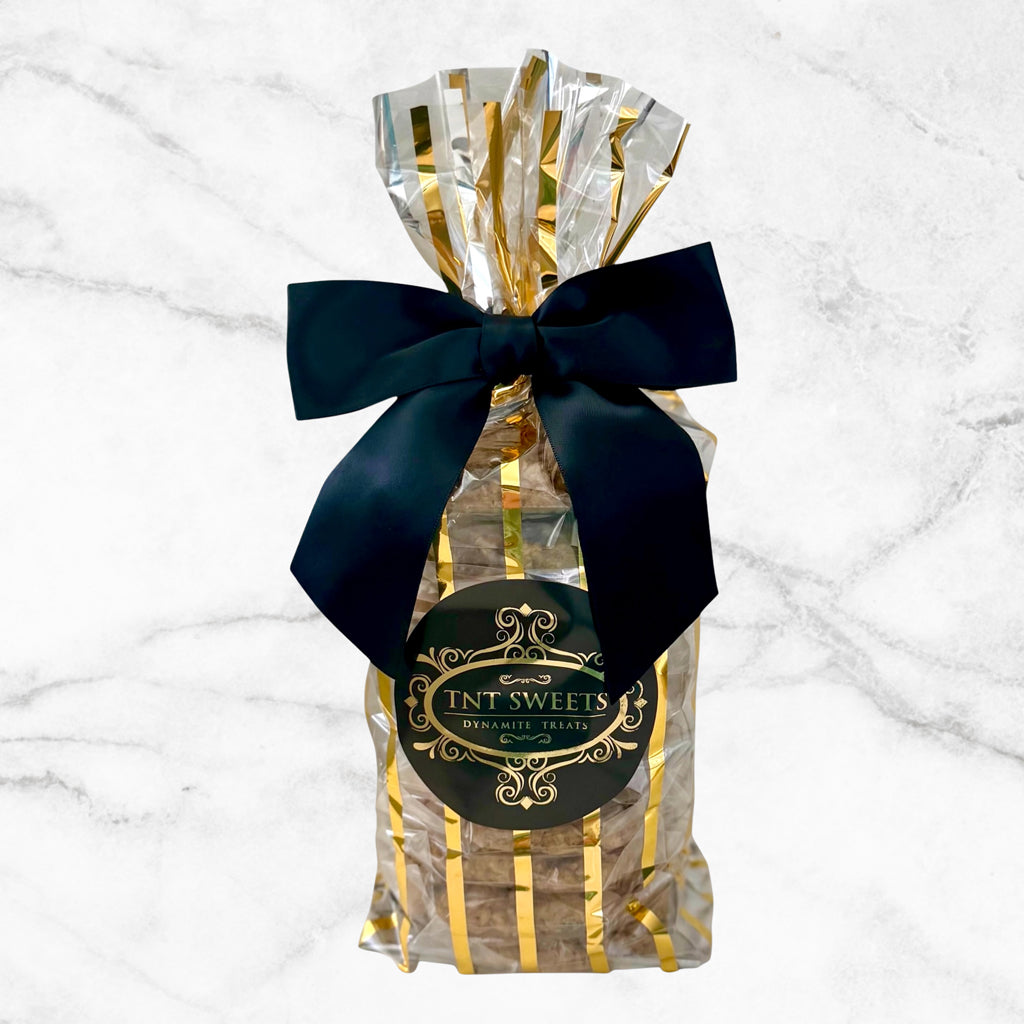 TNT Sweets, The Opus 12-piece Cookie Assortment featuring twelve artisan cookies across up to two signature flavors, presented in the Gold Stripe Wrap with a black satin bow and Signature TNT Sweets seal.