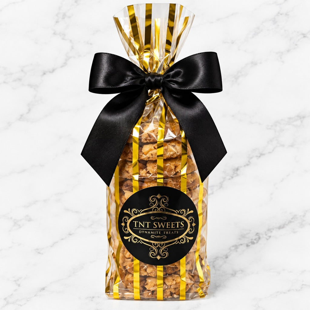 TNT Sweets Peanut Butter Reserve cookies in a clear gold-striped gift bag finished with a black satin bow and black-and-gold logo.