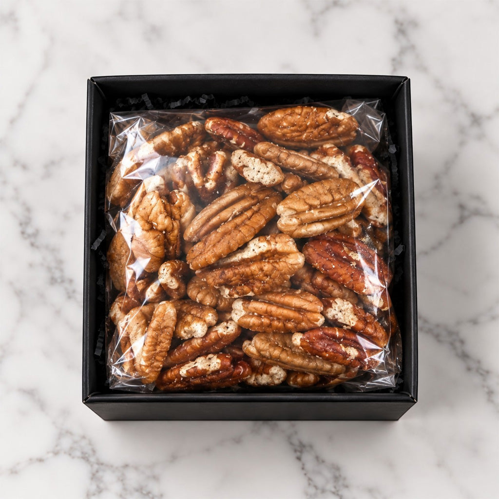 TNT Sweets half-pound pecans in an open keepsake box on a white marble background.