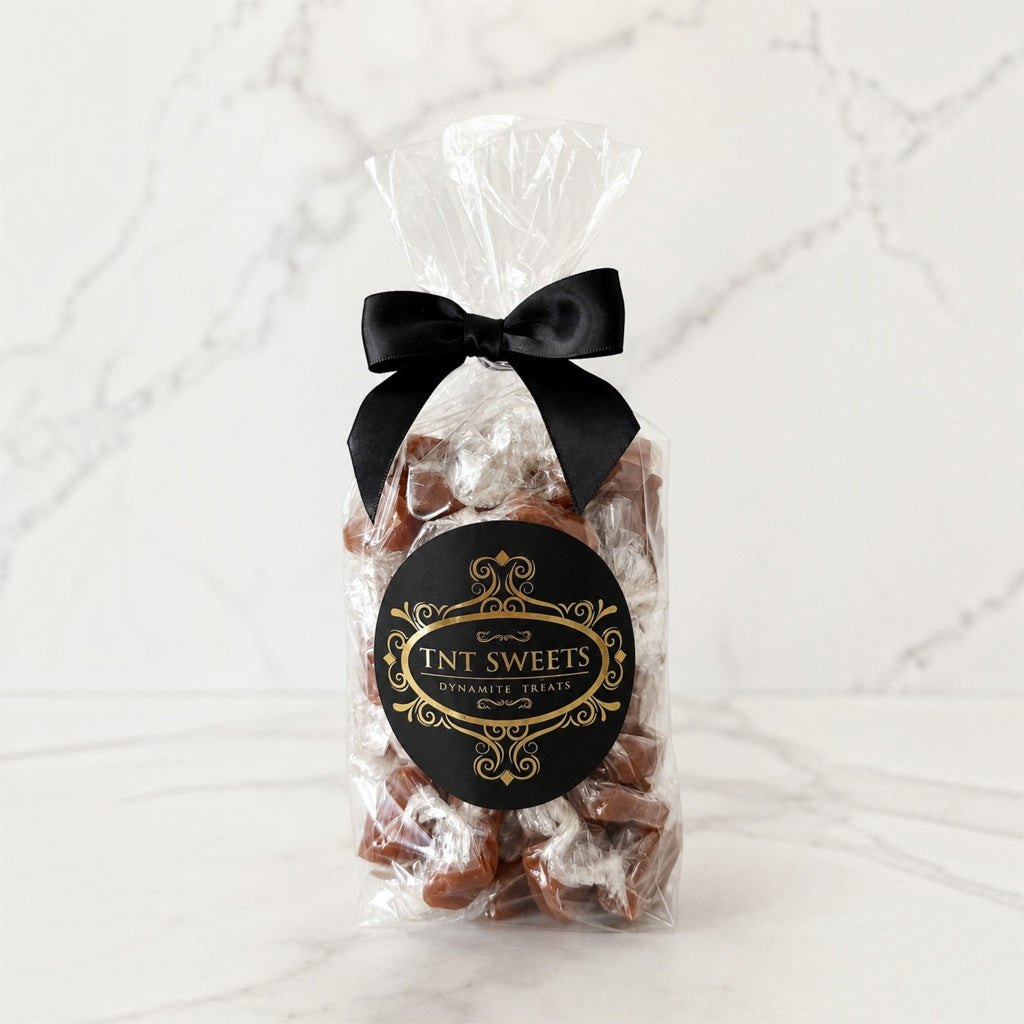 Clear one-pound bag of The Velvet Heat cayenne sea salt caramels, finished with a black satin bow and black-and-gold TNT Sweets label.