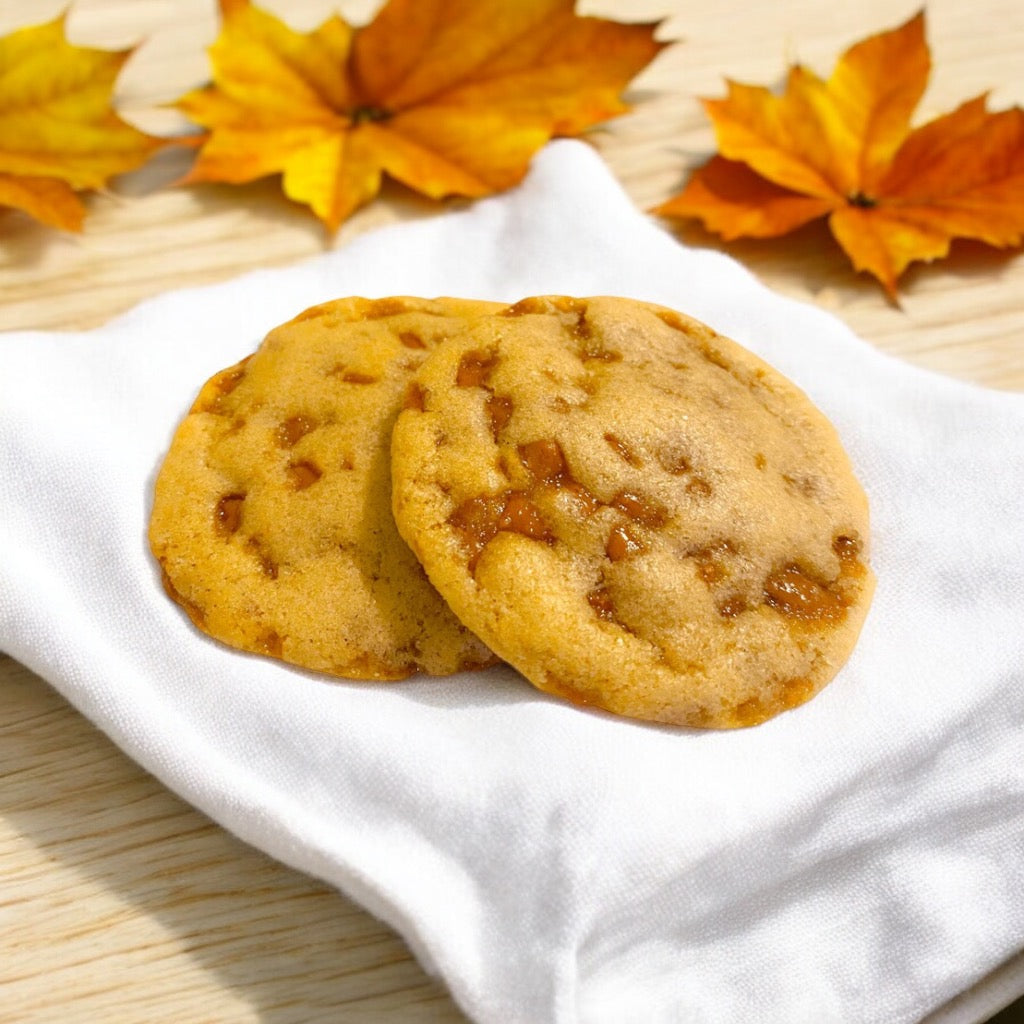 Two Toffee cookies on a linen napkin with scattered fall leaves.